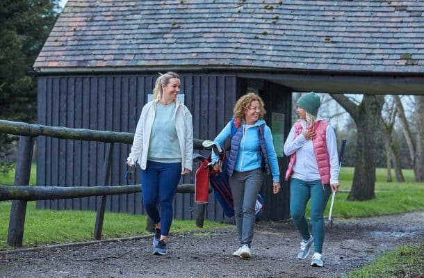 3 women walking through a golf course