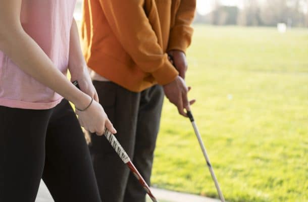People stood on a field holding golf putters
