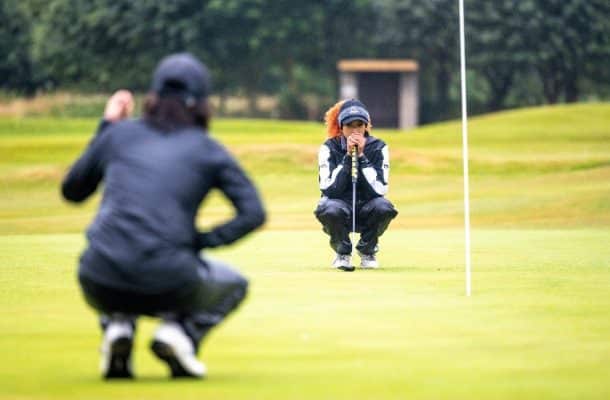 Two people on a golf course crouching down inspecting the golf shot