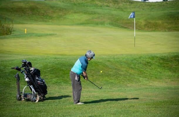 a person wearing blue playing golf on a green golf course